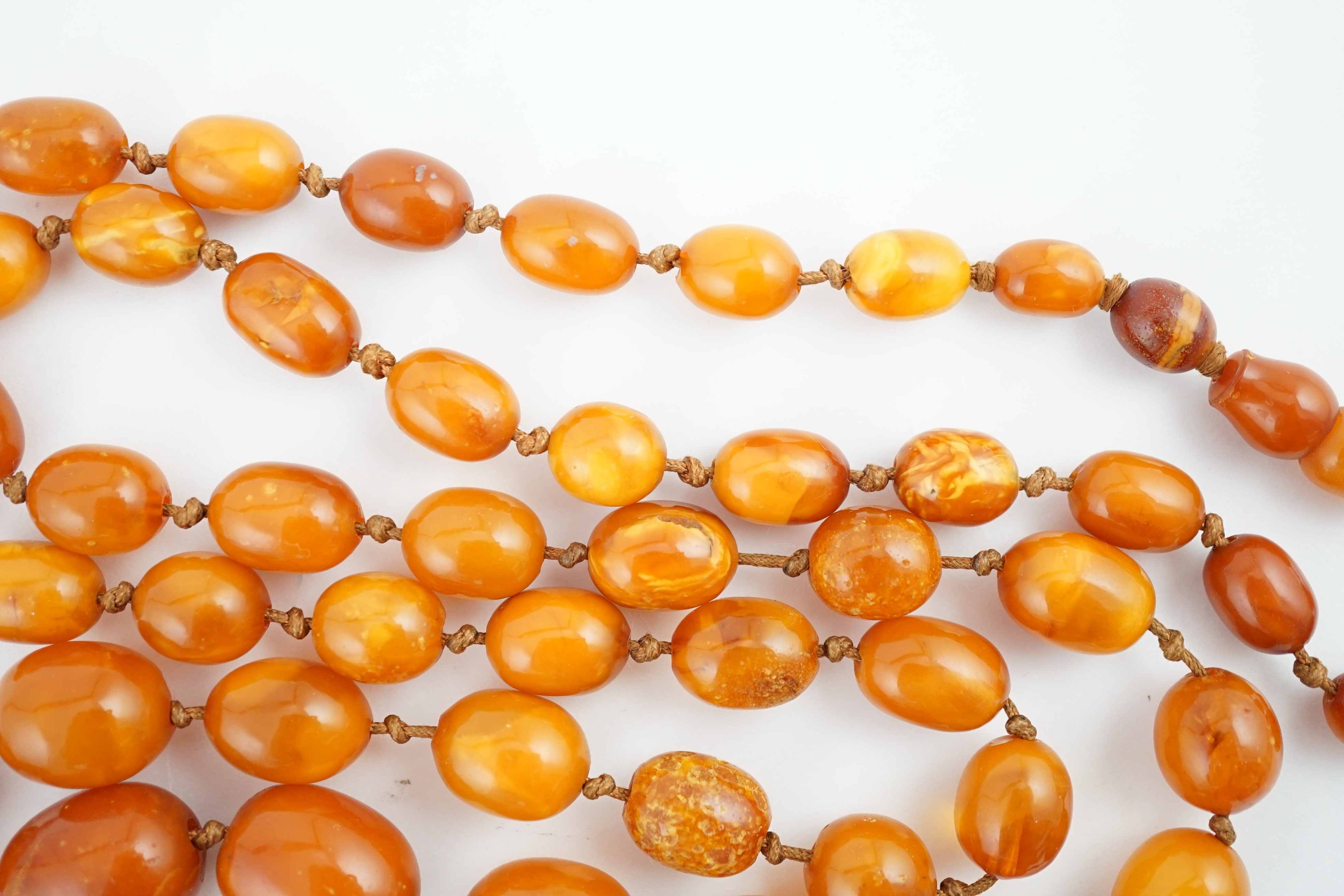 A long single strand graduated amber bead necklace